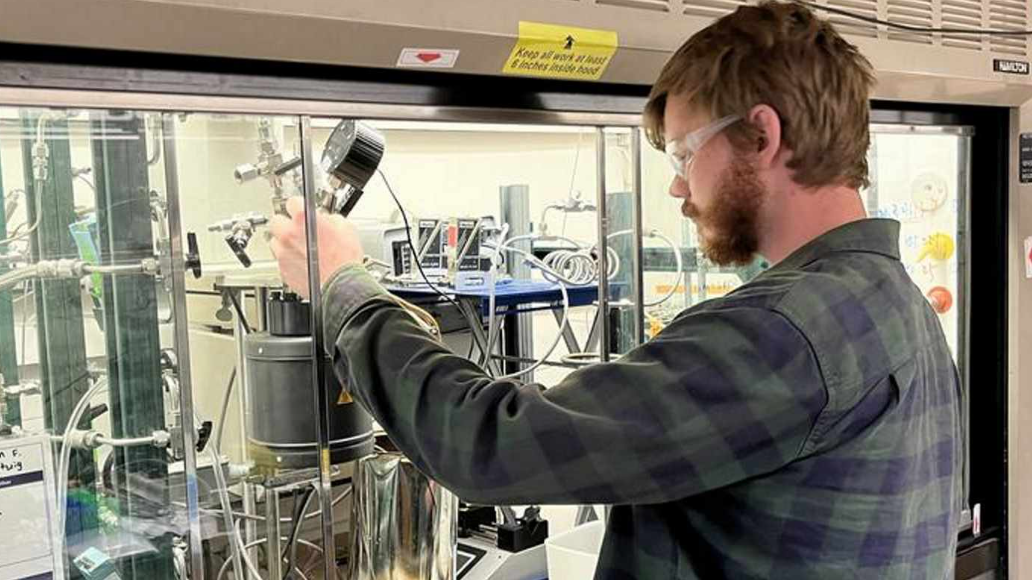 Richard Conk, a graduate student on the plastic project, adjusting the reaction chamber components– credit BNL/SWNS