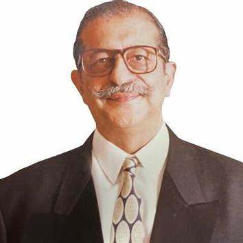 Areez Khambatta, the founder of Rasna, wearing glasses and a suit, smiling warmly.